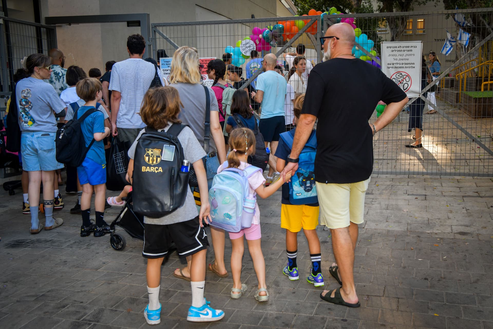 הורים ותלמידים ממתינים בשערי בית הספר בבוקר פתיחת שנת הלימודים